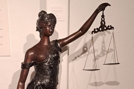 Bronzeskulptur der Justizia, einer Frau mit Waage und Schwert.
