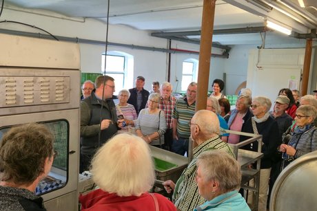 Die Gruppe steht vor einem großen Kasten, der sich als Spargelschälmaschine entpuppt.