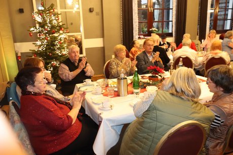 Mehrere Menschen sitzen an festlich gedeckten Tischen.