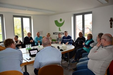 Menschen sitzen gemeinsam um einen großen Tisch herum