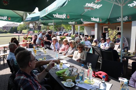 Mehrere Mitglieder sitzen im Biergarten an gedeckten Tischen.