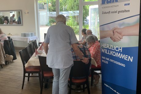 Ein Gast steht an einem Tisch und redet mit den anderen