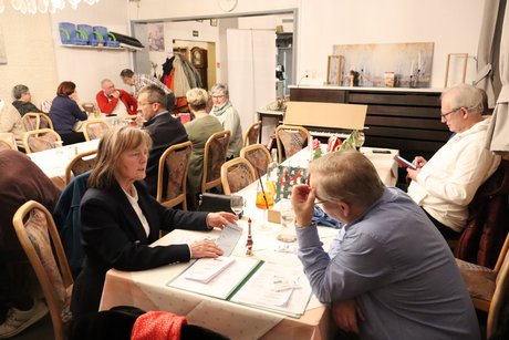 Menschen sitzen an gedeckten Tischen.