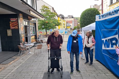 Ein Mann versucht mit der Hilfe eines Rollators ein Hindernis zu überwinden.