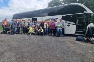 Die Reisegruppe steht vor einem großen, weißen Reisebus.