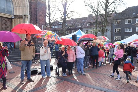 Auftaktveranstaltung internationale Wochen gegen Rassismus in Essen Holsterhausen. Viele Menschen stehen mit bunten Schirmen nebeneinander .