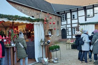 Auch im Schloss-Innenhof sind vor Mauer- und Fachwerk-Fassade weiße, mit Tannengrün geschmückte Pavillon-Zelte aufgebaut, in denen weihnachtliche Dekorationen zum Kauf angeboten werden.