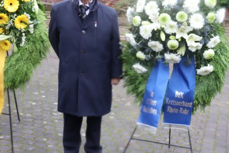 Kranzniederlegung zum Volkstrauertag auf dem Südwestfriedhof. Ein Mann steht neben einem aufgestellten Kranz.