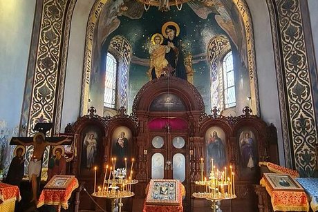 Blick ins Innere der russisch-orthodoxen Kirche mit kunstvoll geschnitztem Altar und bemalter Kuppel.