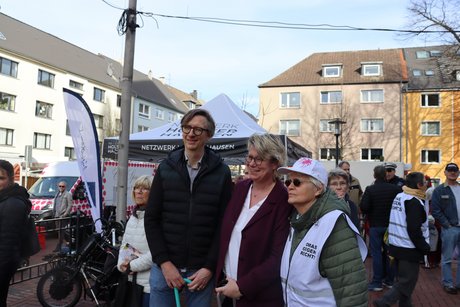 Auftaktveranstaltung internationale Wochen gegen Rassismus in Essen Holsterhausen. 3 Personen stehen zusammen und dahinter sieht man weitere Menschen bei der Veranstaltung.