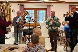 Ein Blechbläser-Quartett steht in der Saalmitte und musiziert