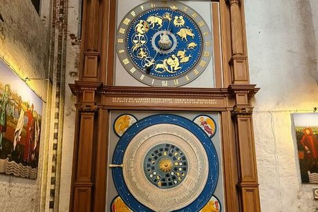 Kunstvoll mit Schnitzereien umsäumte, und mit goldenen Sternzeichen verzierte, elektronische Uhr im Dom.