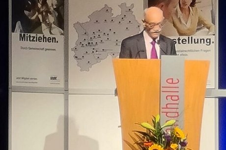 Horst Vöge steht an einem blumengeschmückten Rednerpult.