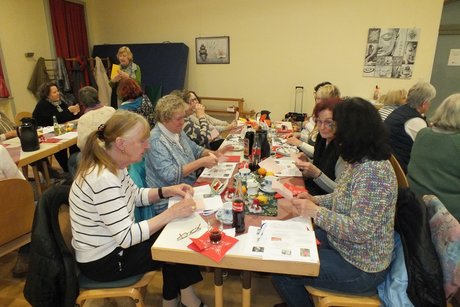 Jahresabschlusstreffen der Frauenvertreterinnen. Frauen sitzen an Tischen und falten Blätter zu Figuren.