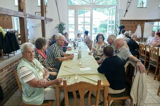 Menschen sitzen gemeinsam an einem langen Tisch.