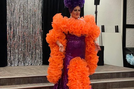 Künstler Künstler in einen bezauberten Kostüm (Kleid orangsch und lila mit einem Kopfschmuck der gleichen Farben)