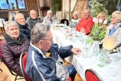 An Tischen sitzen Mitglieder in einer Runde zusammen und warten auf die Berichte.
