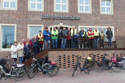 ca. 30 Personen sehen in Regenkleidung auf einer Treppe vor einem Caf&eacute;
