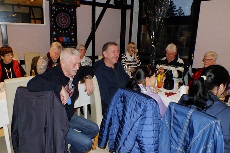 Mitglieder und Gäste sitzen an gedeckten Tischen.