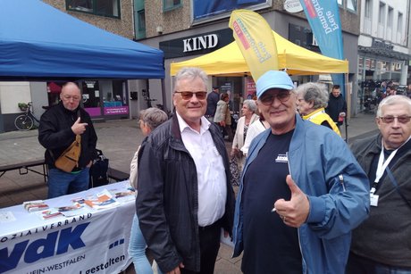 Mehrere Menschen stehen vor einem VdK Info-Stand.