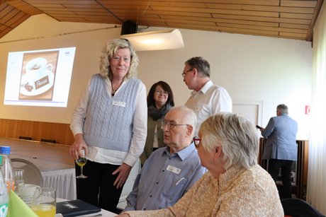 Zwei sitzende Personen unterhalten sich mit drei stehenden Personen.