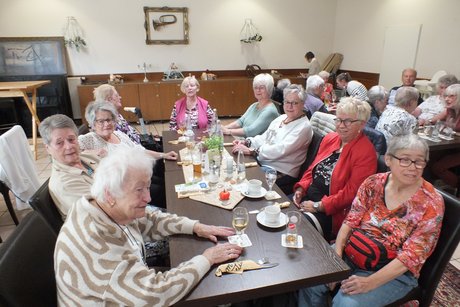 Mehrere Menschen sitzen an langen Tischen.
