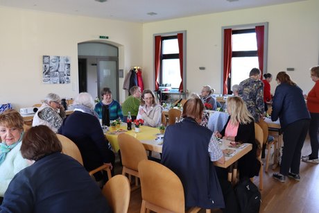 Treffen der Vertreterinnen der Frauen im Mehrgenerationenhaus. An mehreren Tischen sitzen Menschen und unterhalten sich.