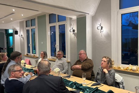 Menschen sitzen an Tischen und unterhalten sich