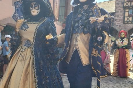 Prächtige venezianische Karnevalsköstüme vor historischer Kulisse in Riquewihr.