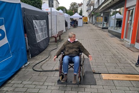 Eine Frau im Rollstuhl versucht allein die Hindernisse zu überwinden