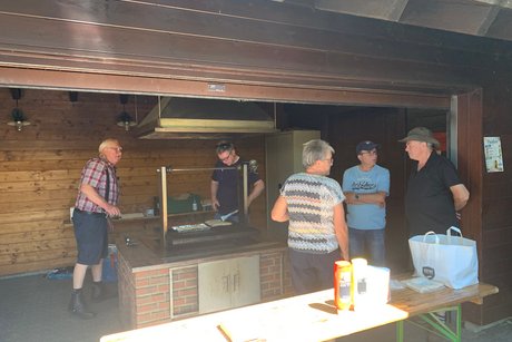 Personen grillend und bei einer Unterhaltung in einer Grillh&uuml;tte