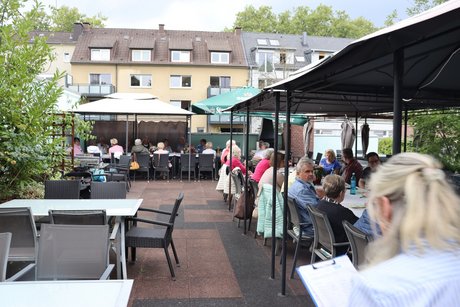 Grillnachmittag vom VdK Ortsverband Altendorf gemeinsam mit dem Ortsverband Borbeck. An langen Tischen sitzen die Teilnehmer des Grillnachmittags.