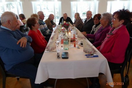 Eine Gruppe Menschen sitzt gemeinsam an einem Tisch.
