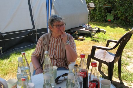 Grillnachmittag. Eine Frau sitzt an einem Gartentisch.