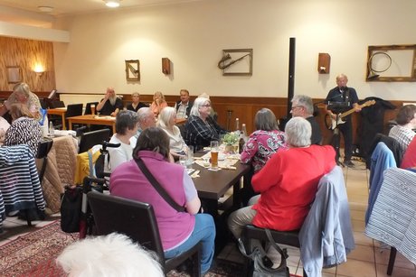 Mitglieder und G&auml;ste h&ouml;ren dem Musiker zu.