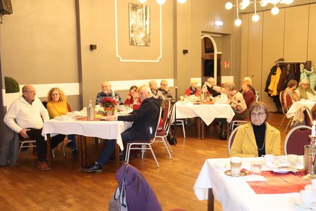 Mehrere Menschen sitzen an festlich gedeckten Tischen.