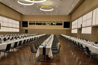 Großer menschenleerer Saal mit langen, festlich gedeckten Tischen.