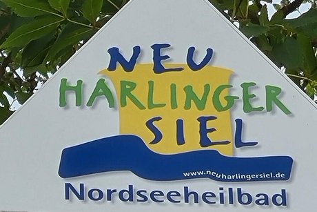 Abfotografiertes Schild mit der grünblauen Aufschrift Neuharlingersiel Nordseeheilbad.