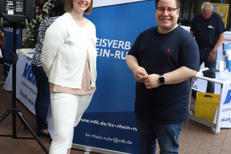 Eine Frau und ein Man stehen vor einem VdK Werbeaufsteller.