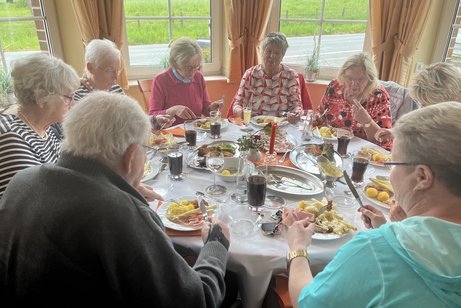 Eine Gruppe bei Tisch, deren Mitglieder es sich schmecken lassen