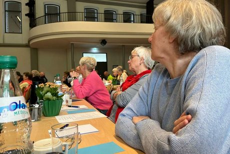 Viele Menschen sitzen an langen Tischreihen