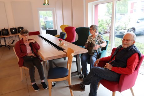 3 Menschen sitzen an einem Tisch.