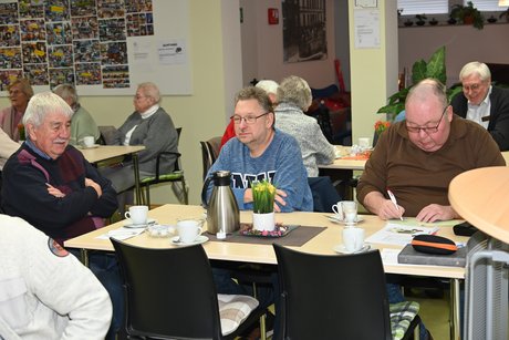 Mitglieder sitzen an einem Tisch und unterhalten sich