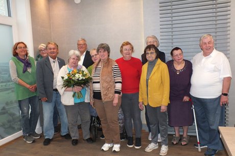 Zw&ouml;lf Personen stehen f&uuml;r ein Gruppenbild zusammen.