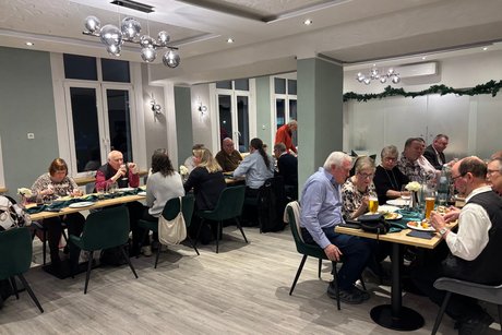 Menschen sitzen an Tischen und unterhalten sich