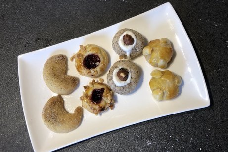Vier verschiedene Sorten Weihnachtspl&auml;tzchen sind jeweils paarweise auf einem eckigen Teller angerichtet.