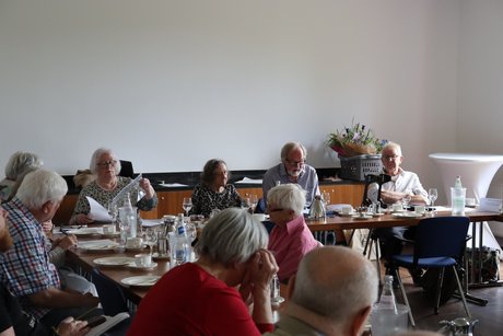 Jahreshauptversammlung 2026 Mehrere Personen sitzen am Tisch und ein Mann liest etwas von einem Zettel ab.