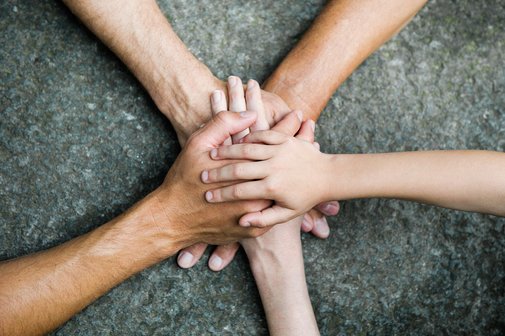 Hände zusammen für Gemeinschaft Fünf Personen legen jeweils eine Hand aufeinander, so dass ein Kreis bzw. ein Stern entsteht