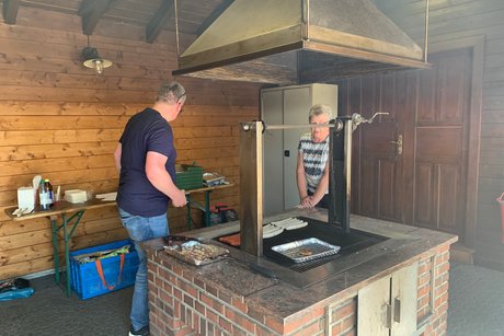 Zwei Personen am Grill mit W&uuml;rstchen und Grillk&auml;se