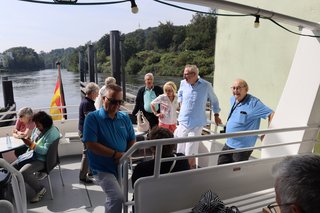 Teilnehmer genießen die Sonne auf dem Außendeck.